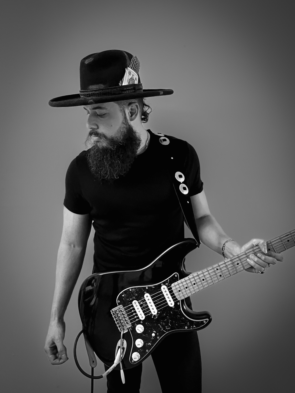 Black-and-white full-length portrait of Will Plus holding an electric guitar