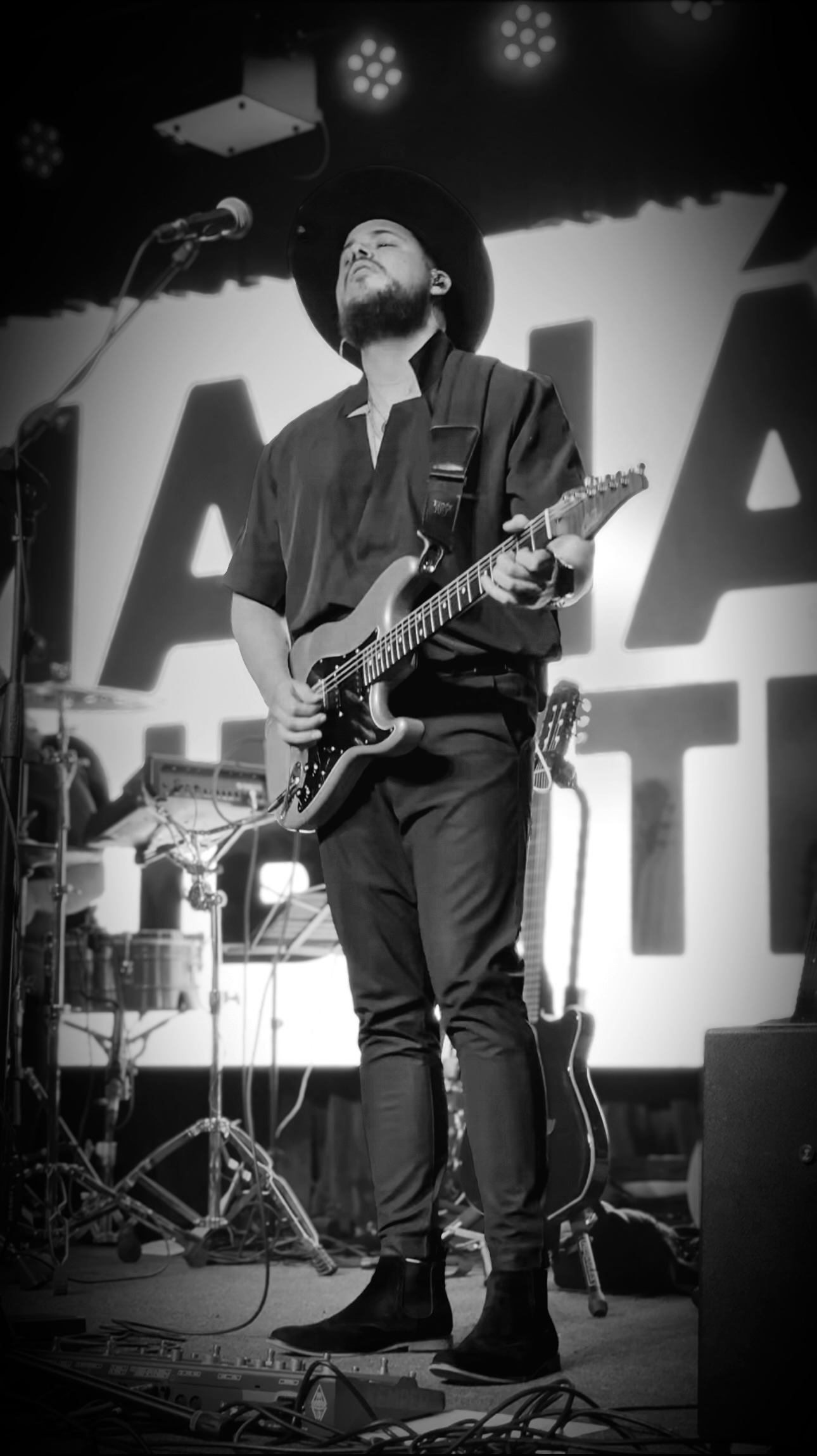 Will Plus playing an electric guitar solo during a live black-and-white stage performance