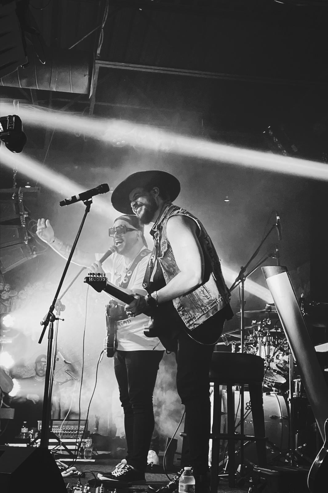 Will Plus smiling on stage with electric guitar during a live concert